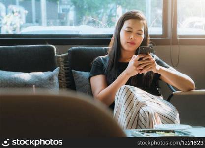 young asia woman reading message in smartphone at coffee shop