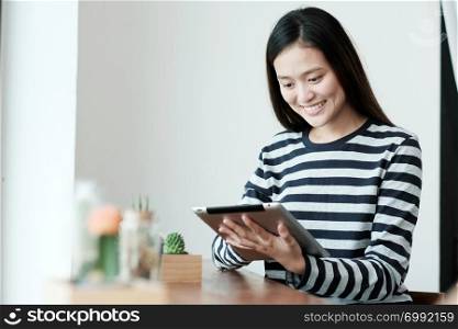 Young asia woman using tablet while sitting in cafe background, People technology and lifestyle