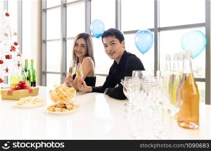 Young asian adult couple celebrating New year christmas holiday with sparkling wine together in living room of big condominium in big city