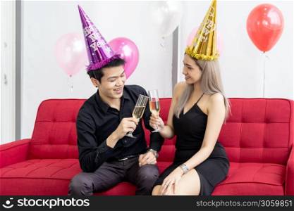 Young asian adult couple celebrating New year christmas holiday with sparkling wine together in living room of big condominium in big city