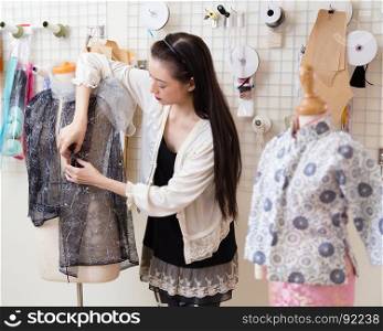 Young Asian American fashion designer dressing a mannequin