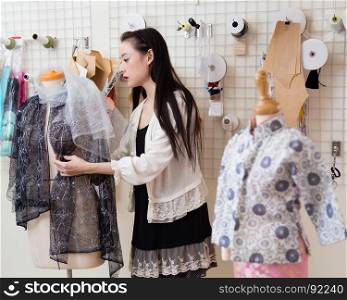Young Asian American fashion designer dressing a mannequin
