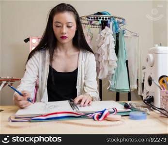 Young Asian American fashion designer sketching design