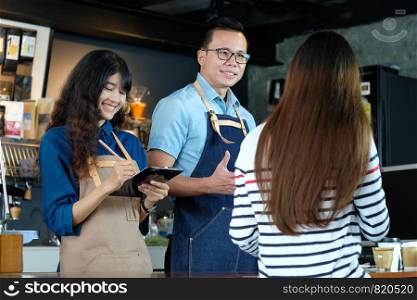 Young asian barista taking customer order at coffee cafe counter with smiling face, food and drink business concept