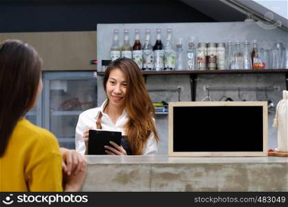Young asian barista taking note, order, at coffee cafe counter with smiling face, food and drink business concept