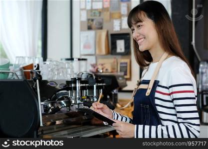 Young asian barista taking note, order, at coffee cafe counter with smiling face, food and drink business concept