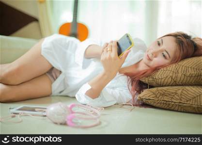 Young asian beautiful woman with smart phone and listening to music at home
