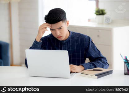 Young asian business man headache during working on laptop computer with deadline on desk at home, businessman with failure exhausted and tired, stress and worried, frustrated and unsuccessful.