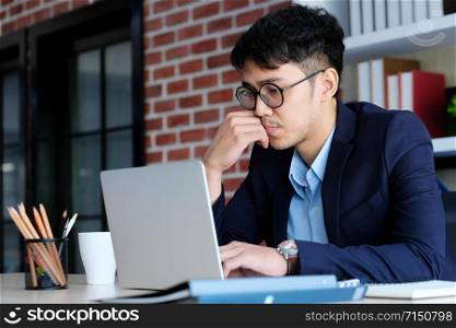 Young asian businessman concentrate on working with laptop computer at office, business people and office lifestyle concept