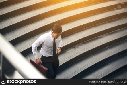 Young asian businessman holding briefcase and running to meeting at underground office building.