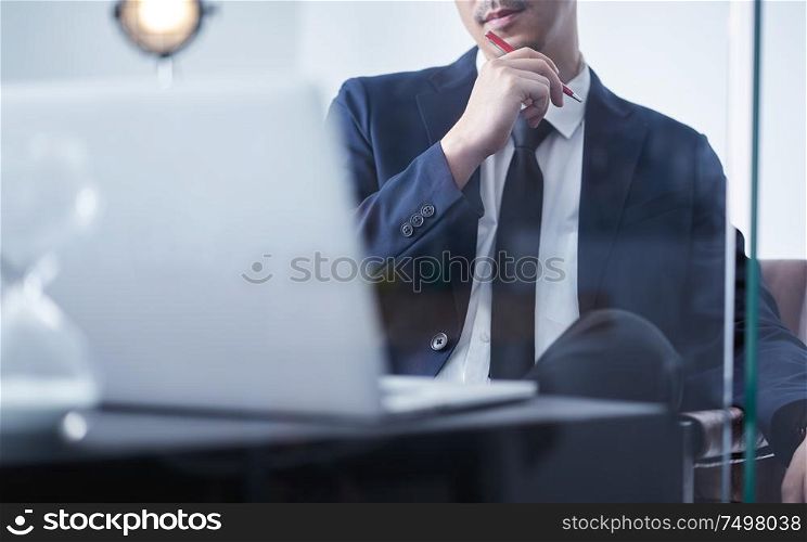 Young asian businessman holding pen and think about the financial plan