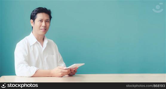 Young asian businessman using tablet with smiling face, positive emotion, at office, casual office life concept