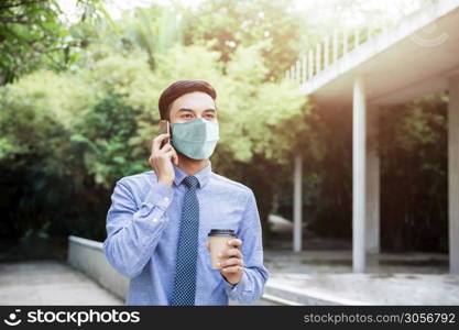 Young Asian Businessman Wearing a Surgical Mask and Using a Smart Phone. Healthcare in New Normal Lifestyle Concept