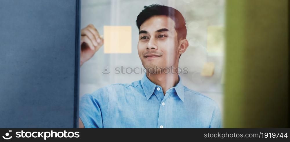 Young Asian Businessman Working in a Meeting Room. Smiling and Concentrate on Document Note on Board