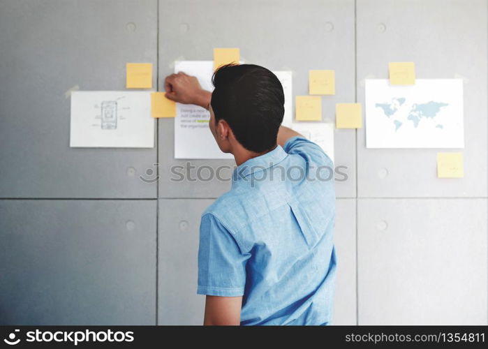 Young Asian Businessman Working in Office Meeting Room. Man Analyzing Data Plans and Project. Concentrate on Document Note on Board