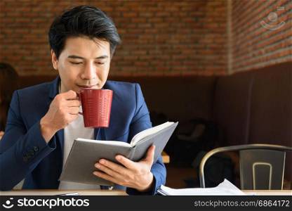 young asian businessman working while drinking red cup coffee in the office