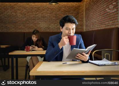 young asian businessman working while drinking red cup coffee in the office