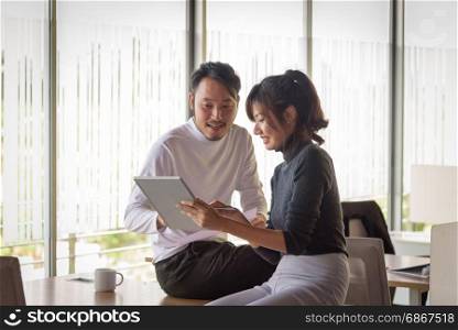 young asian businesspeople ,man and woman, using tablet in startup office