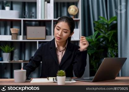 Young asian businesswoman is diligently working and taking notes in her modern office workspace, demonstrating professionalism as attractive and diligent office lady. Enthusiastic. Young asian businesswoman working in her modern office. Enthusiastic
