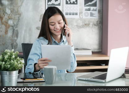 Young asian businesswoman working and talking phone at office table, business casual lifestyle