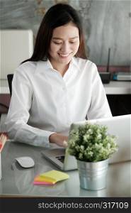 Young asian businesswoman working with laptop computer at office with happy emotion, working at home, office casual lifestyle concept