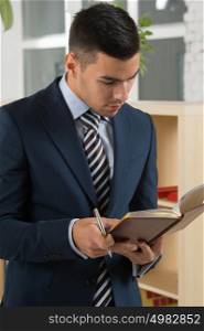 Young asian caucasian business man holding a book while planning his schedule at office