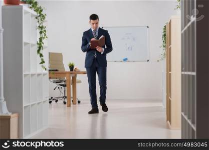 Young asian caucasian business man holding a book while planning his schedule at office