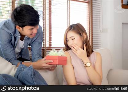 Young asian couple celebrate birthday together, asia man giving gift box present to woman for surprise at living room, female feeling happy and excited anniversary, holiday valentine concept.