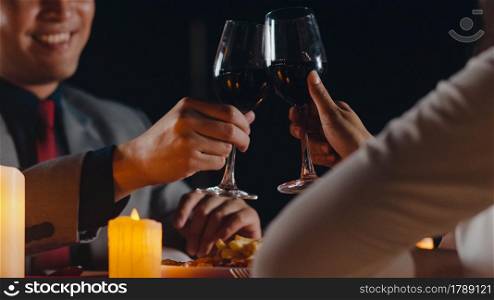 Young asian couple celebrate romantic dinner with drinking wine in rooftop restaurant at night city with happy moment celebrate anniversary. Love relationship, celebrating new year concept.