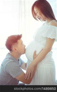 Young asian couple expecting baby standing together indoors