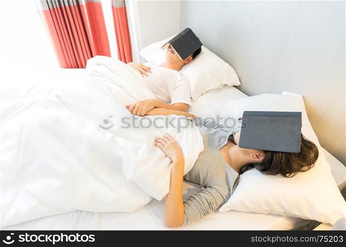 Young Asian Couple laid in a bed reading a book in bedroom of contemporary house for modern lifestyle concept