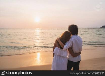 Young asian couple looking beautiful sunset on the beach, Summer vacation concept