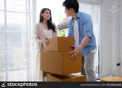 Young asian couple moving in new house. Asian man and woman holding boxes.