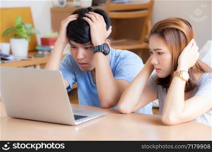 Young asian couple stressed and worried about finance of problem business together, man and woman looking laptop and frustrated, family unhappy and depression about debt, lifestyle concept.