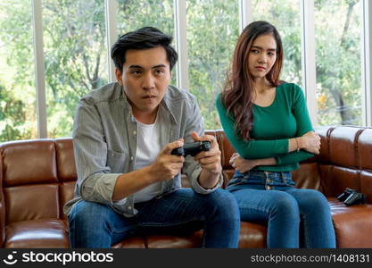 Young Asian couple suffers from computer games addiction. Family problem concept.