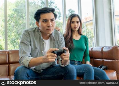 Young Asian couple suffers from computer games addiction. Family problem concept.