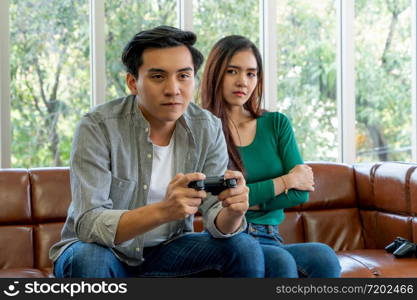 Young Asian couple suffers from computer games addiction. Family problem concept.