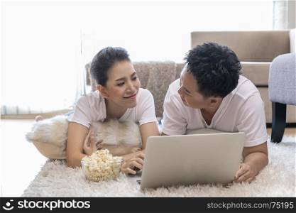 Young Asian Couples using laptop together in bedroom of contemporary house for modern lifestyle concept