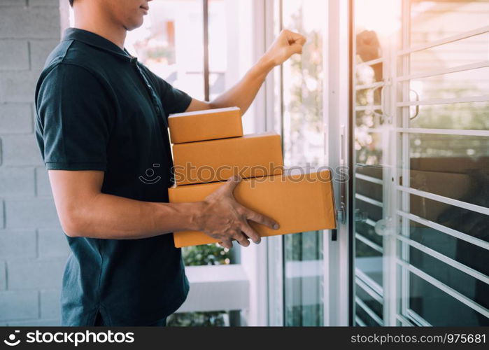 Young asian courier is using the hand of the knock at the door to deliver the goods.