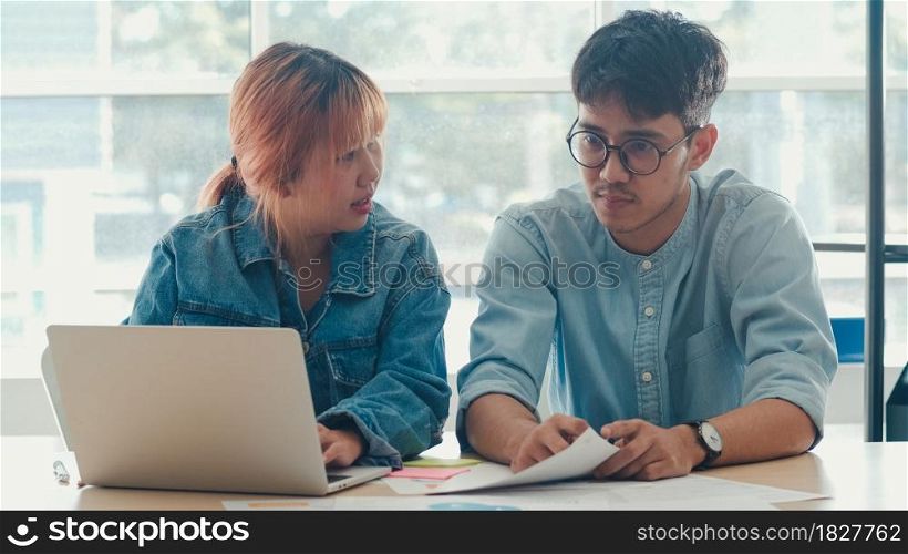Young Asian creative team meeting working on laptop. Group of business man and woman looking document paper, discuss and think new idea, business situation, teamwork in modern office concept.
