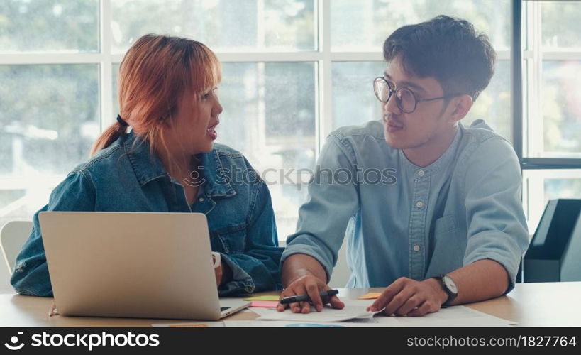 Young Asian creative team meeting working on laptop. Group of business man and woman looking document paper, discuss and think new idea, business situation, teamwork in modern office concept.