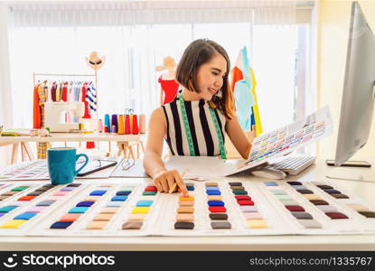 Young Asian designer woman working with computer and choosing multicolor chart at workplace, small business startup, Business owner entrepreneur, modern freelance job lifestyle concept. asean people