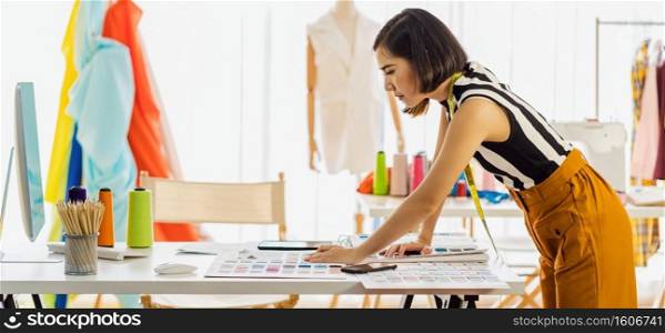 Young Asian designer woman working with computer and choosing multicolor chart at workplace, small business startup, Business owner entrepreneur, modern freelance job lifestyle concept. asean people