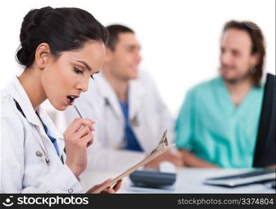 Young asian doctor thinking with the pen, others blurred behind over white background
