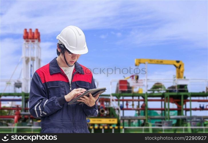 Young Asian engineer using digital tablet to working his job with blurred background of oil tanker in shipyard area