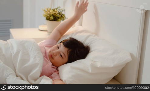 Young Asian girl wake up at home. Asia japanese woman child kid relax rest after sleep all night lying on bed, feel comfort and calm in bedroom at home in the morning concept.