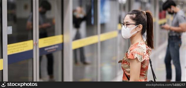 young Asian girl wearing Surgical face mask protect coronavirus inflection, Happy tourist woman wating public train. social distancing, new normal and life after covid-19 pandemic