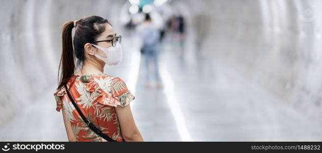 young Asian girl wearing Surgical face mask protect coronavirus inflection, Happy tourist woman walking in public subway station. social distancing, new normal and life after covid-19 pandemic