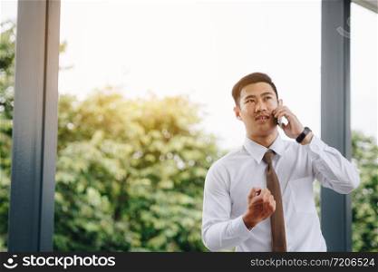 Young asian handsome businessman talking on phone and happiness for work.