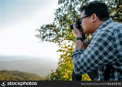 Young Asian hiker man and backpack use camera to take pictures in forest. copy space